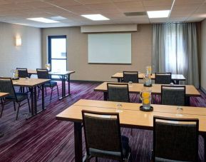 Hotel meeting room with tables, in a classroom format, facing a whiteboard and window.