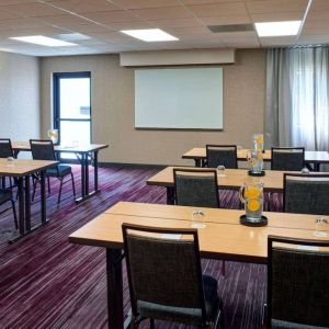 Hotel meeting room with tables, in a classroom format, facing a whiteboard and window.