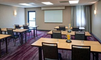 Hotel meeting room with tables, in a classroom format, facing a whiteboard and window.