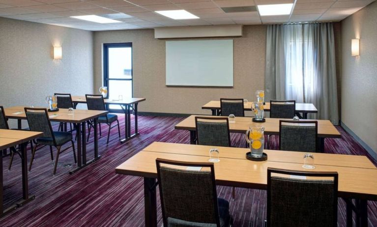 Hotel meeting room with tables, in a classroom format, facing a whiteboard and window.