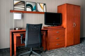 Guest room workspace in Sonesta Select Whippany Hanover, featuring a TV, lamp, desk, and chair.