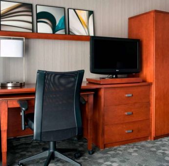 Guest room workspace in Sonesta Select Whippany Hanover, featuring a TV, lamp, desk, and chair.