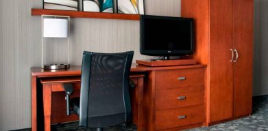 Guest room workspace in Sonesta Select Whippany Hanover, featuring a TV, lamp, desk, and chair.