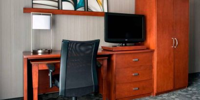 Guest room workspace in Sonesta Select Whippany Hanover, featuring a TV, lamp, desk, and chair.