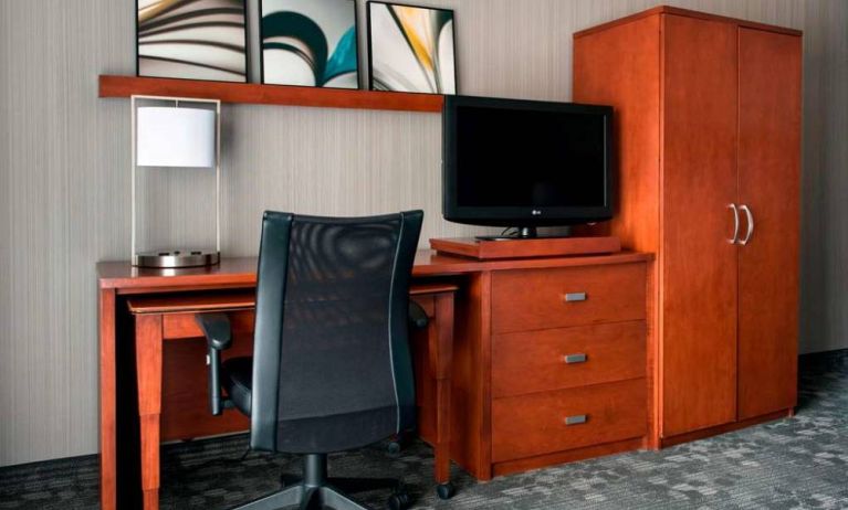 Guest room workspace in Sonesta Select Whippany Hanover, featuring a TV, lamp, desk, and chair.