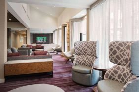 The lobby lounge at Sonesta Select Whippany Hanover features sofas and armchairs, coffee tables, large windows, and a large TV.