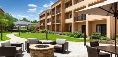 The hotel fire pit has comfy armchairs around it, with a shaded table and chairs nearby.