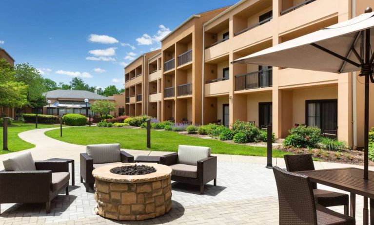 The hotel fire pit has comfy armchairs around it, with a shaded table and chairs nearby.