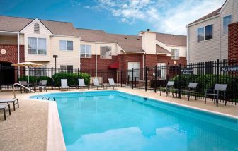 Sonesta ES Suites Annapolis’ outdoor pool has a shaded table and chairs, loungers, and chairs by the side.