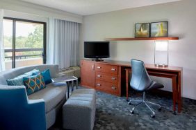 Sonesta Select Raleigh Durham Airport Morrisville guest room living area, furnished with workspace desk and chair, and a sofa and TV.