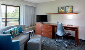 Sonesta Select Raleigh Durham Airport Morrisville guest room living area, furnished with workspace desk and chair, and a sofa and TV.