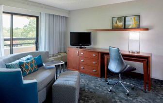 Sonesta Select Raleigh Durham Airport Morrisville guest room living area, furnished with workspace desk and chair, and a sofa and TV.