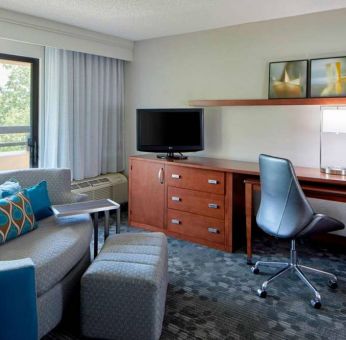 Sonesta Select Raleigh Durham Airport Morrisville guest room living area, furnished with workspace desk and chair, and a sofa and TV.