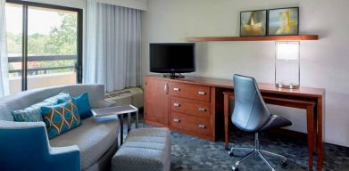 Sonesta Select Raleigh Durham Airport Morrisville guest room living area, furnished with workspace desk and chair, and a sofa and TV.