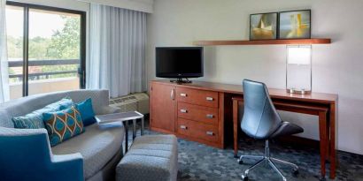 Sonesta Select Raleigh Durham Airport Morrisville guest room living area, furnished with workspace desk and chair, and a sofa and TV.