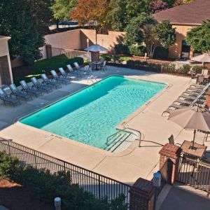 The outdoor pool at Sonesta Select Raleigh Durham Airport Morrisville has sun loungers by the side, as well as shaded tables and chairs.