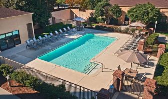 The outdoor pool at Sonesta Select Raleigh Durham Airport Morrisville has sun loungers by the side, as well as shaded tables and chairs.