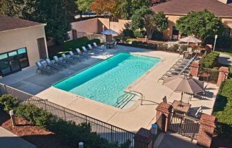 The outdoor pool at Sonesta Select Raleigh Durham Airport Morrisville has sun loungers by the side, as well as shaded tables and chairs.