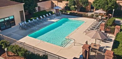 The outdoor pool at Sonesta Select Raleigh Durham Airport Morrisville has sun loungers by the side, as well as shaded tables and chairs.