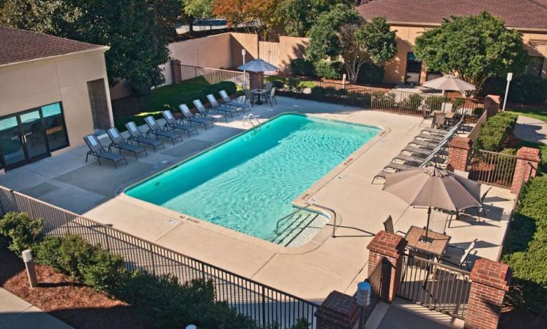 The outdoor pool at Sonesta Select Raleigh Durham Airport Morrisville has sun loungers by the side, as well as shaded tables and chairs.