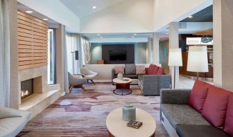 Sonesta Select Raleigh Durham Airport Morrisville’s lobby lounge is furnished with comfy chairs, coffee tables, and sofas, plus a fireplace and TV.