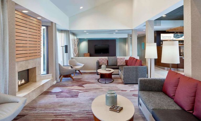 Sonesta Select Raleigh Durham Airport Morrisville’s lobby lounge is furnished with comfy chairs, coffee tables, and sofas, plus a fireplace and TV.