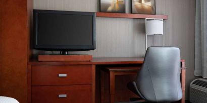 Sonesta Select Phoenix Camelback guest room workspace, including desk, chair, and lamp, plus a TV.