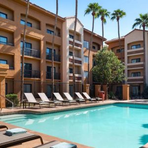 Sonesta Select Phoenix Camelback’s outdoor pool has sun loungers by the side, a shaded area, and tall palm trees.