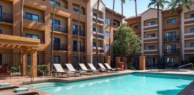 Sonesta Select Phoenix Camelback’s outdoor pool has sun loungers by the side, a shaded area, and tall palm trees.