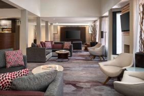 Lounge in the hotel lobby, furnished with comfy chairs and large sofas, coffee tables and multiple large televisions.