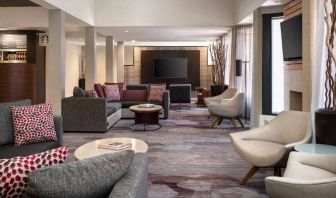 Lounge in the hotel lobby, furnished with comfy chairs and large sofas, coffee tables and multiple large televisions.