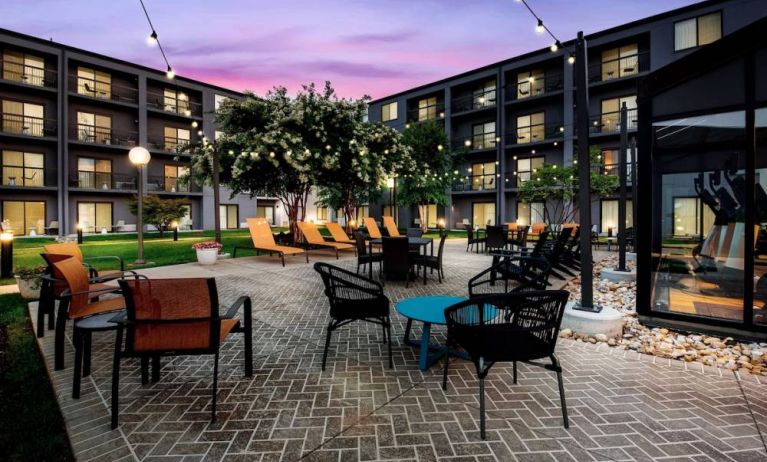 Sonesta Select Philadelphia Airport’s patio features a brickwork surface, tables and chairs, sun loungers, and pleasant trees nearby.