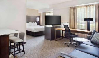 Double bed guest room in Sonesta ES Suites Raleigh Cary, featuring TV and sofa, plus workspace desk, chair, and lamp.