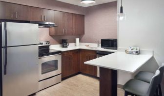 Sonesta ES Suites Raleigh Cary guest room kitchen, fitted with oven, microwave, fridge-freezer, and sink.