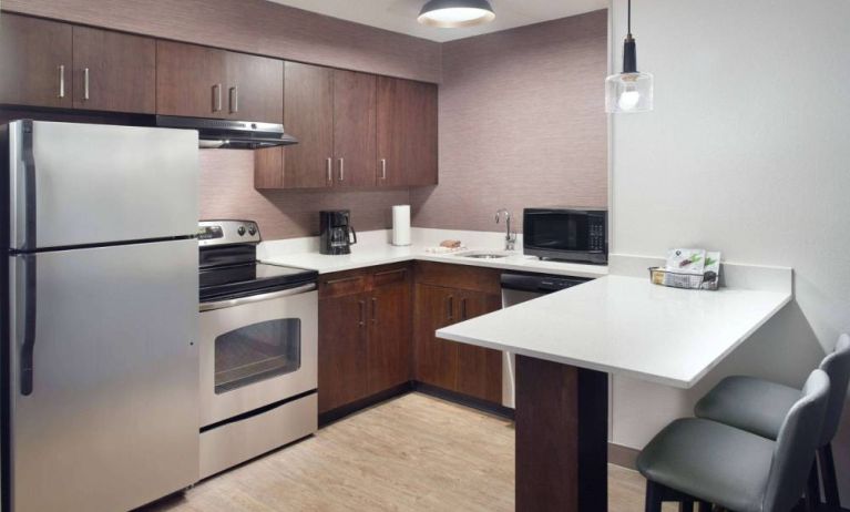 Sonesta ES Suites Raleigh Cary guest room kitchen, fitted with oven, microwave, fridge-freezer, and sink.