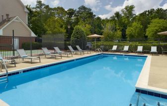 Sonesta ES Suites Raleigh Cary’s outdoor pool has shaded tables and chairs, and numerous sun loungers, by the side.