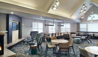 Sonesta ES Suites Raleigh Cary’s lobby has extensive seating and range of table sizes, plus large windows, TV, and a fireplace.