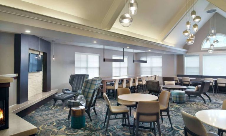 Sonesta ES Suites Raleigh Cary’s lobby has extensive seating and range of table sizes, plus large windows, TV, and a fireplace.