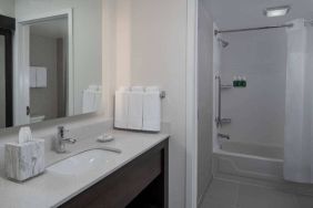 Guest bathroom in Sonesta ES Suites Fairfax Fair Lakes, with shower-equipped bath, mirror, and sink.