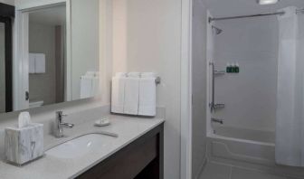 Guest bathroom in Sonesta ES Suites Fairfax Fair Lakes, with shower-equipped bath, mirror, and sink.