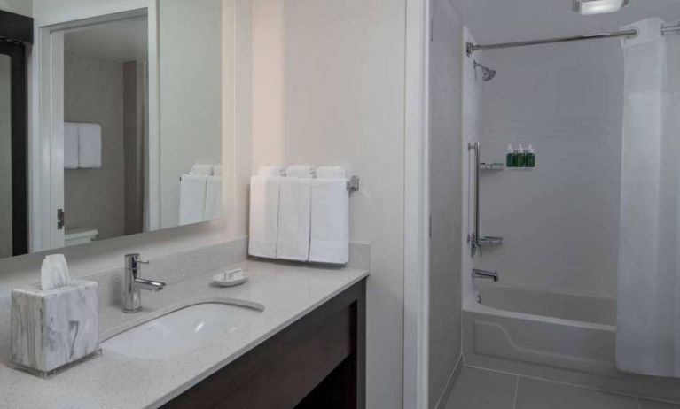 Guest bathroom in Sonesta ES Suites Fairfax Fair Lakes, with shower-equipped bath, mirror, and sink.