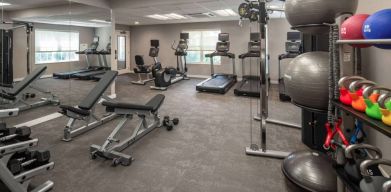 The fitness center at Sonesta ES Suites Fairfax Fair Lakes is equipped with dumbbells, kettlebells, gym balls, and assorted exercise machines.