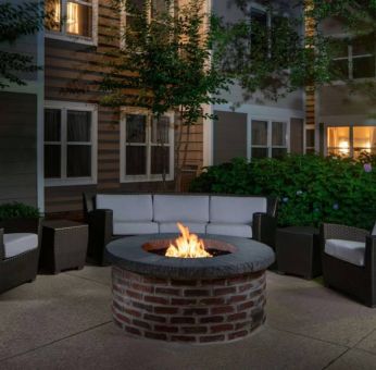 Sonesta ES Suites Fairfax Fair Lakes’ fire pit has armchairs, coffee tables, and a sofa where guests can relax and socialize.