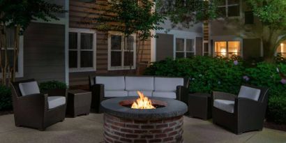 Sonesta ES Suites Fairfax Fair Lakes’ fire pit has armchairs, coffee tables, and a sofa where guests can relax and socialize.