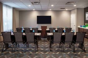 Hotel meeting room, with tables and twelve seats facing a lectern and wall-mounted TV.