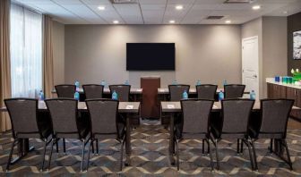 Hotel meeting room, with tables and twelve seats facing a lectern and wall-mounted TV.