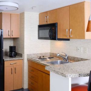 Sonesta ES Suites Dallas Medical Market Center guest room kitchen, with microwave, fridge-freezer, and hob.