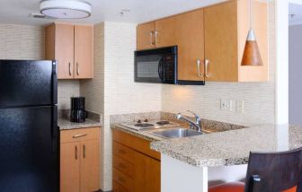 Sonesta ES Suites Dallas Medical Market Center guest room kitchen, with microwave, fridge-freezer, and hob.