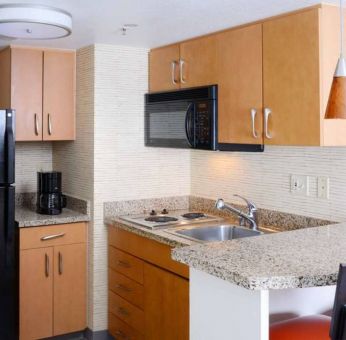 Sonesta ES Suites Dallas Medical Market Center guest room kitchen, with microwave, fridge-freezer, and hob.