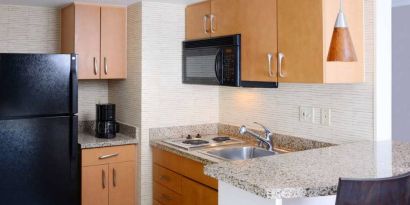 Sonesta ES Suites Dallas Medical Market Center guest room kitchen, with microwave, fridge-freezer, and hob.